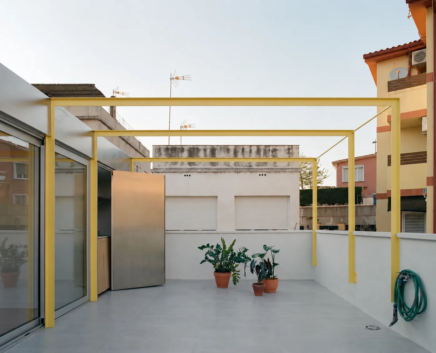 Pérgola amarilla y cocina oculta de acero terraza Casa Miranda Sant Just Desvern